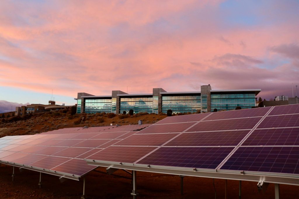 Solarmodule vor einem modernen Gebäude bei Sonnenuntergang, die Technologie für erneuerbare Energien präsentieren.